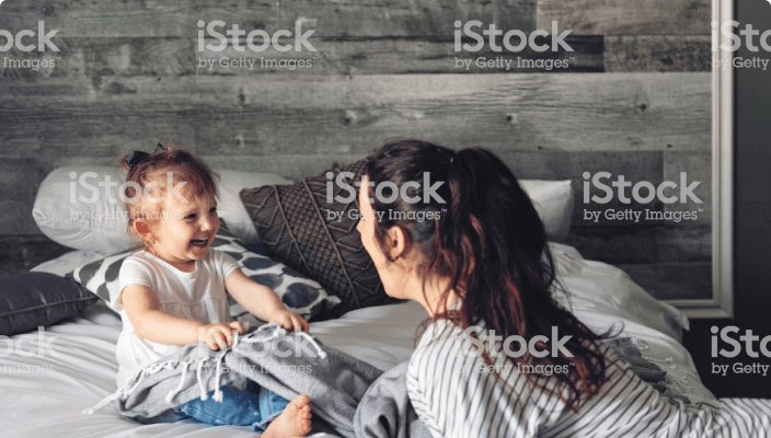 Woman playing with baby on the bed
