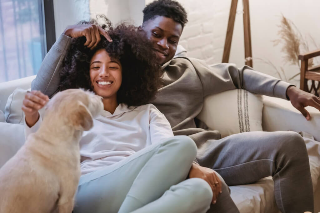 A couple sitting on their couch with their dog